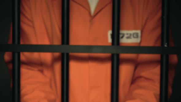 Prisoner Showing Hands in Handcuffs Dangerous Criminal Standing Behind Bars
