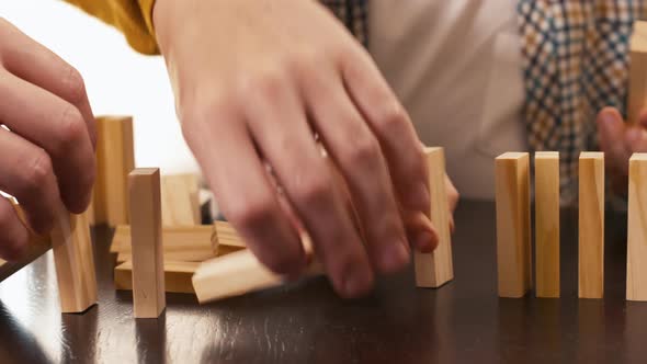 Child and adult man moving wooden construction set bricks