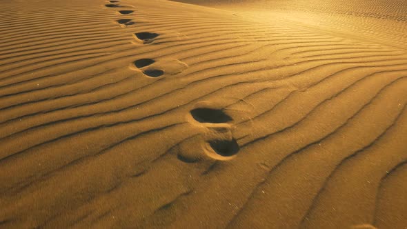 Footprints in the Sand in Desert at Warm Sunset Lights. Сamera Follows Footprints in Big Sand Dune