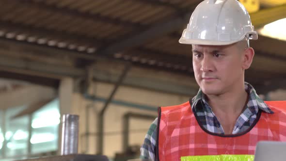 Male foreman using laptop checking on maintenance machine at factory