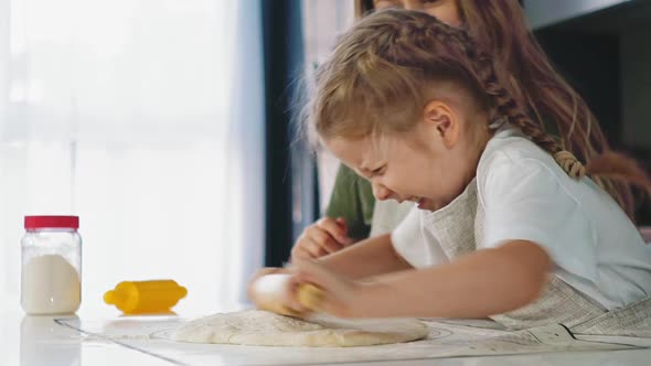 Girl with Mother in Kitchen Cooks Food