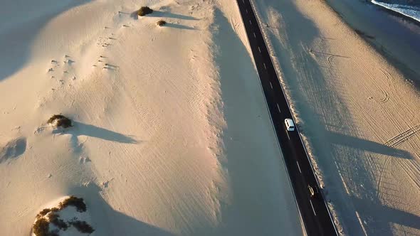 Above view of black asphalt road with desert and sand dunes around - wild outdoor travel car