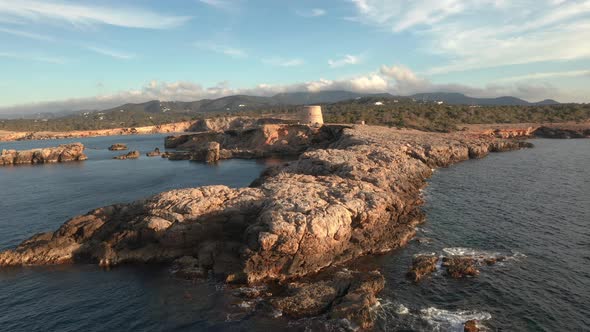 Aerial view of pirate lookout tower in Ibiza during sunset. Showing ocean, cliffs and mountains in t