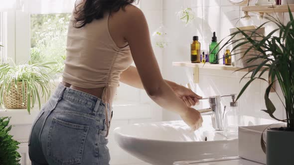 Young Hispanic Woman Dancing with Headphones in Bathroom