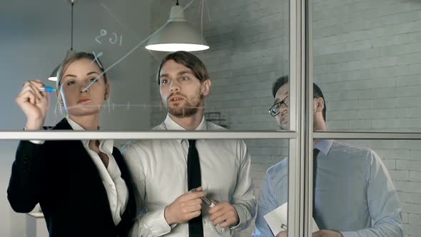 Business people drawing graph on transparent board