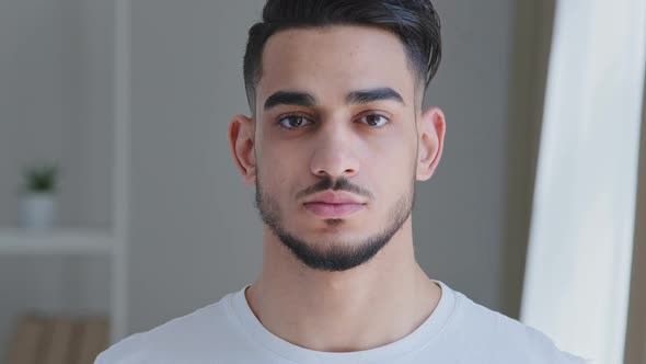 Portrait of Serious Handsome Young Adult Arabic Man with Beard in White Tshirt Stands Posing Indoors