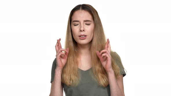 Portrait of Concentrated Woman in Casual Wear with Dyed Blond Hair Keeping Fingers Crossed and