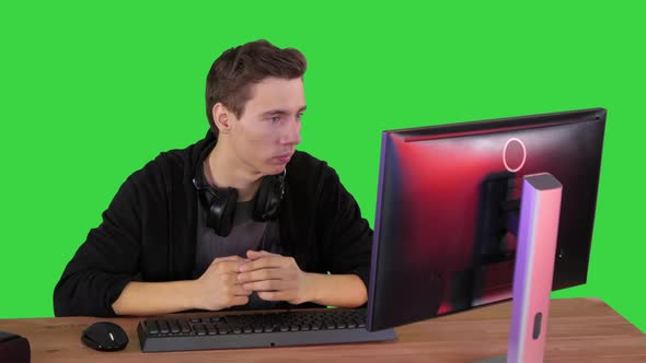 Serious Gamer Sitting at Computer Watching a Game on a Green Screen, Chroma Key