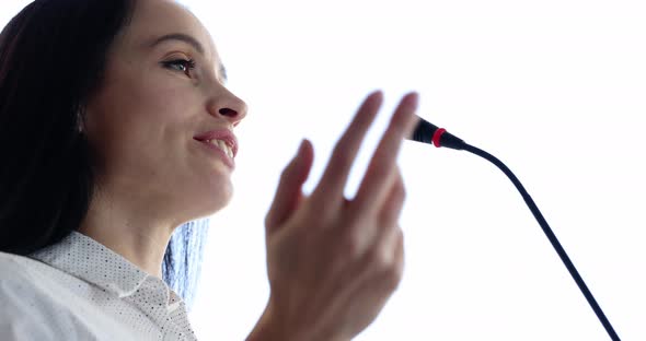 Woman Speaker Speaks Into Microphone Gesturing with Hands