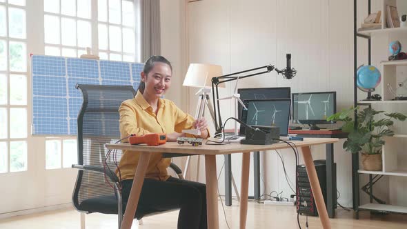 Woman Look At Wind Turbine And Smile To Camera While Working With Laptop Next To The Solar Cell