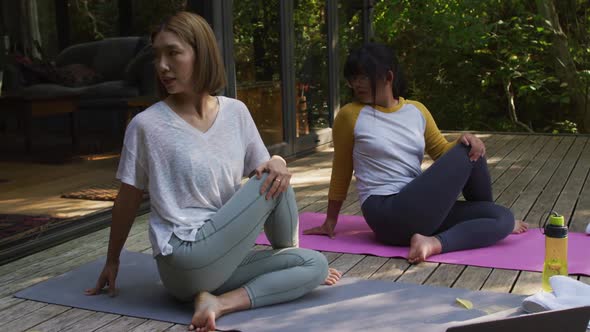 Asian mother and daughter practicing yoga outdoors in garden