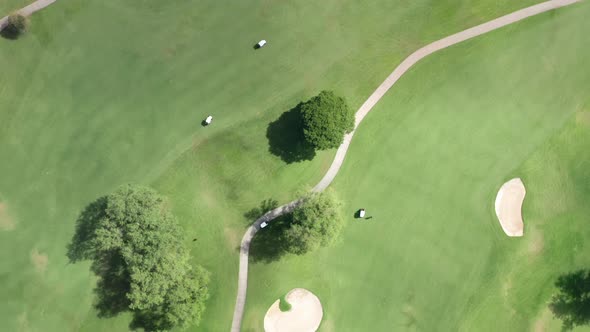 Aerial People in Golf Carts Driving on Green Golf Course on Sunny Summer Day