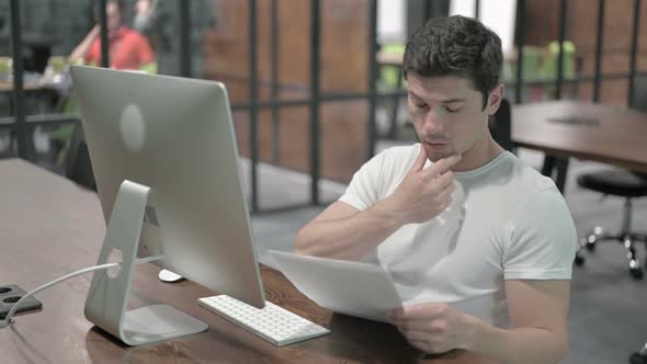 Creative Young Man Studying Documents at Work