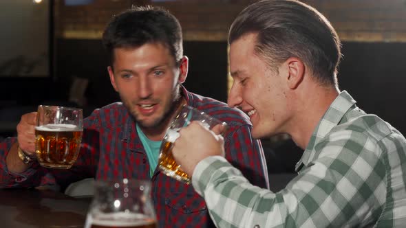 Two Male Friends Enjoying Drinking Beer at the Local Pub