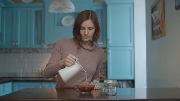 Woman pouring water into glass bowl 