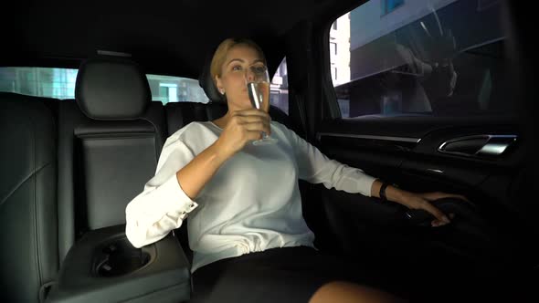 Tired Woman Drinking Champagne on Car Backseat, Driving Home With Private Driver