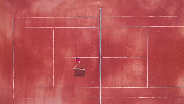 A Man is Relocating a Tennis Net Through the Court in a Top View