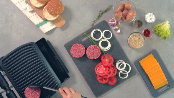 An aerial view of raw burger meat which is being placed on grilling machine by the chef
