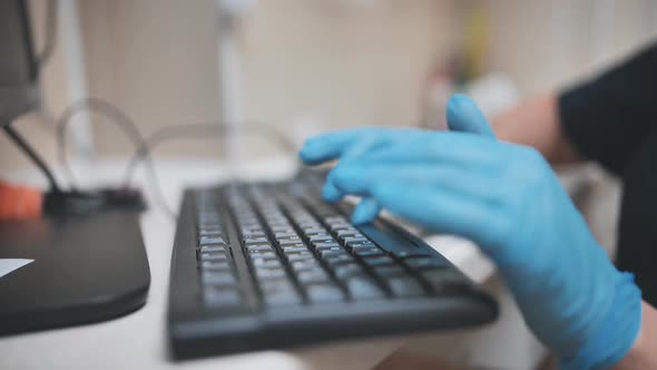 The Veterinarian is Typing on the Keyboard in Blue Gloves