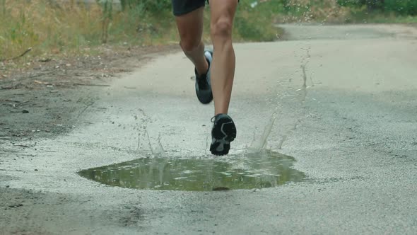 Runner Man Fit Athlete Legs Jogging On Trail Ready To Triathlon. Running Man On Puddle. Runner Jog.