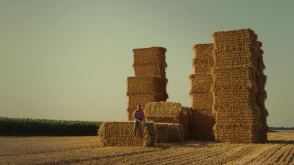 Farmer Resting Hay Stack in Sunset Sunlight