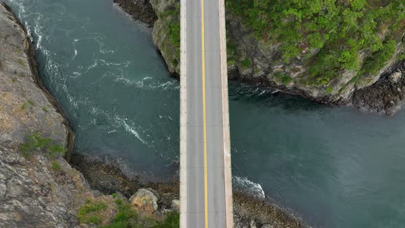 Overhead shot of cars driving over a bridge with water passing underneath.