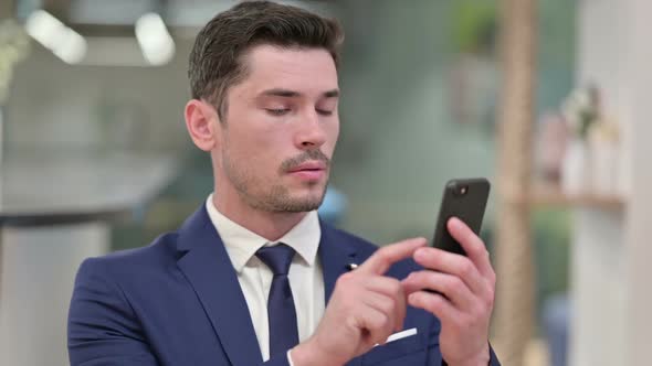 Excited Young Businessman Celebrating Success on Smartphone