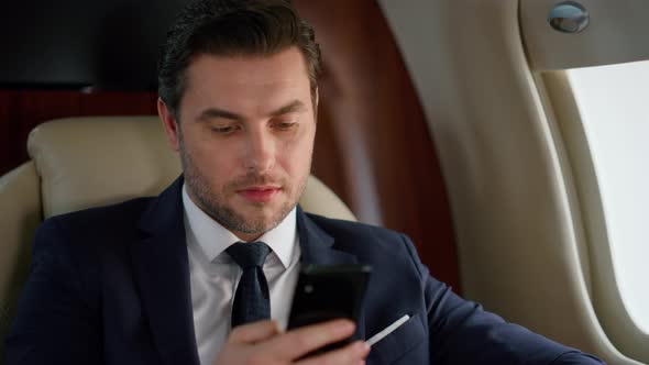 Handsome Entrepreneur Using Smartphone in Plane Closeup