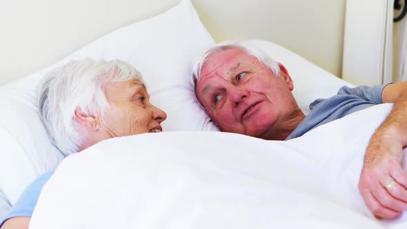 Happy senior couple interacting with each other while lying on bed