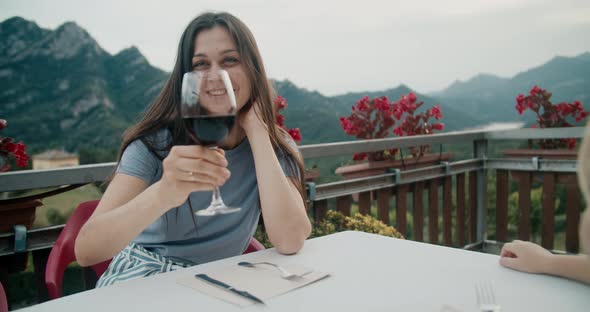 Pleased Woman Clink Glass with Her Boyfriend on Terrace with Epic Mountain View