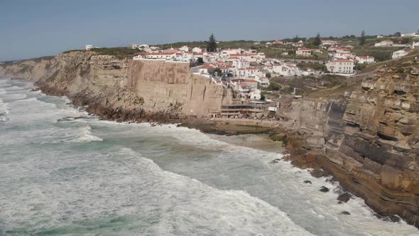 Strong waves washing on cliffs. Panoramic view of coastal town of Azenhas do Mar, Sintra, Portugal