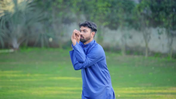 Indian man doing Garudasana or Eagle Yoga Pose in a park