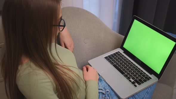 Caucasian Pretty Young Woman Using Laptop with Green Screen Sitting on the Couch Sofa at the Home