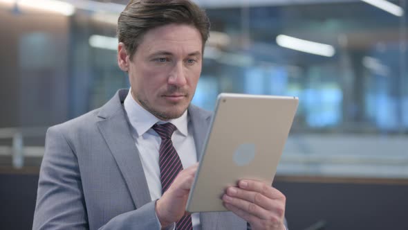 Portrait of Middle Aged Businessman using Digital Tablet