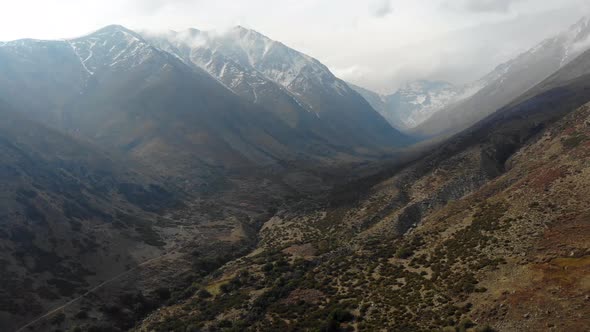 Aerial drone shot ascending in the valley with a view of snowy mountains