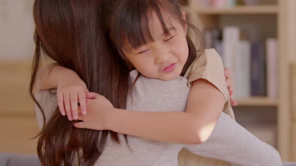 An Asian girl hugs her mom from the front and she also smile