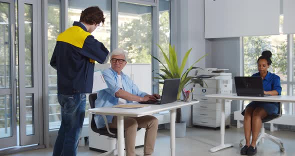 Senior Busy Man Receiving Parcel From Courier in Office
