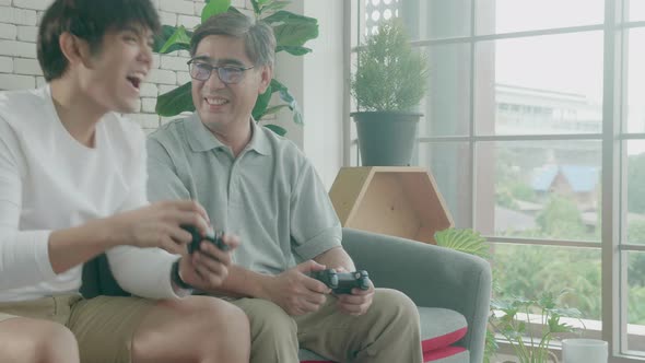 Asian family with father and son play video game on sofa at home.