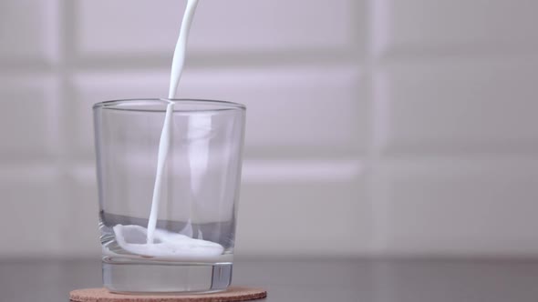 Milk Poured Into A Transparent Glass In The Kitchen Table