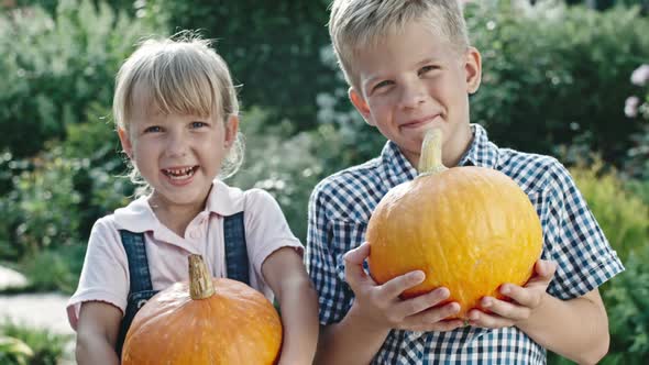 Little Boy and Girl Holding Pumpkins alt