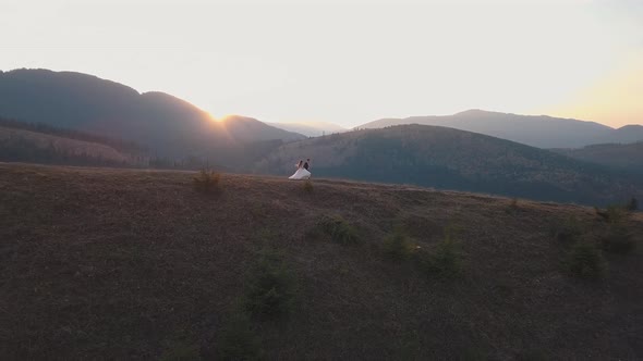 Newlyweds Running on a High Slope of the Mountain. Groom and Bride. Aerial View