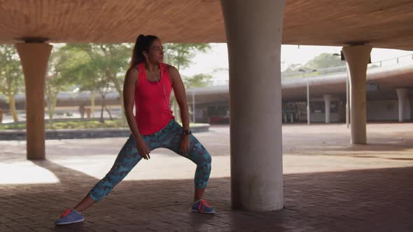 Caucasian woman stretching under a bridge