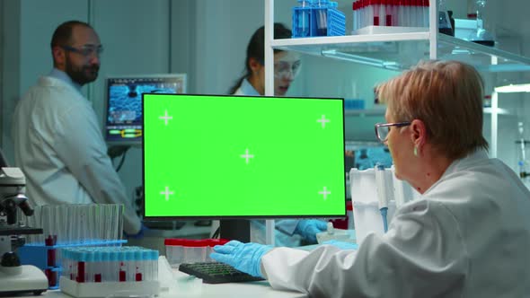 Senior Doctor Working at Computer with Green Screen