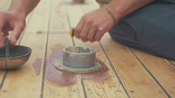 Carpenter unscrewing screws from roof vent on wood boat