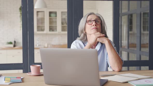 Thoughtful Senior Middle Aged Woman Thinking Sitting at Home Office Table