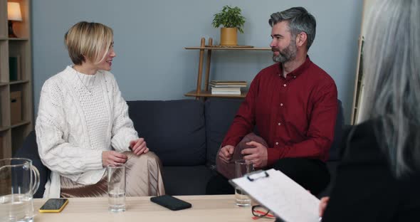 Married Unhappy Couple Discussing Family Problems While Sitting at Psychologist Office