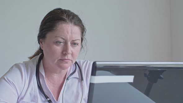The Face of a Female Doctor Who Focuses on Work on the Laptop Light Tension Manifests on the Face alt