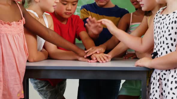 School kids stacking hands in classroom