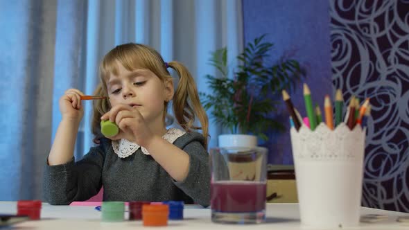 Cute Little Girl Child Sitting and Painting on Paper Drawing Coloring Picture Rainbow with Paints