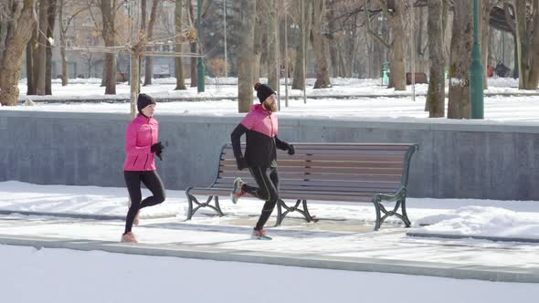 Athletic Pair Jogging in Park in Winter